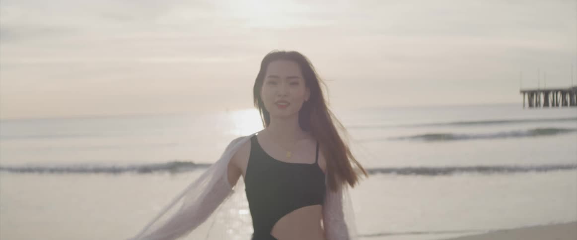 A woman on the beach with the ocean the sky and clouds in the background