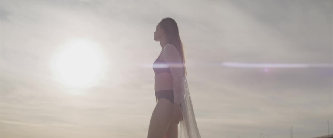 Woman walks pensively on the beach at sunset