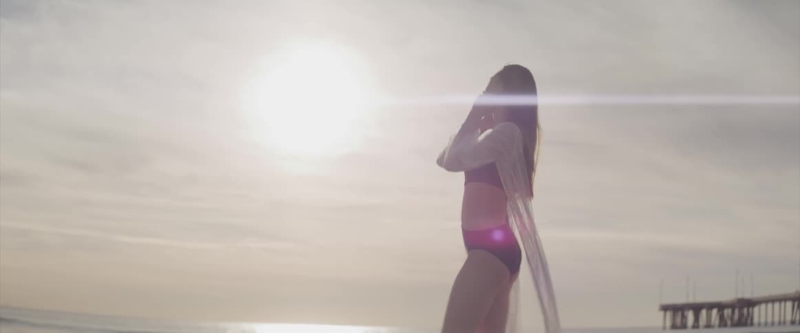 A teenage girl standing on the beach in a bathing suit