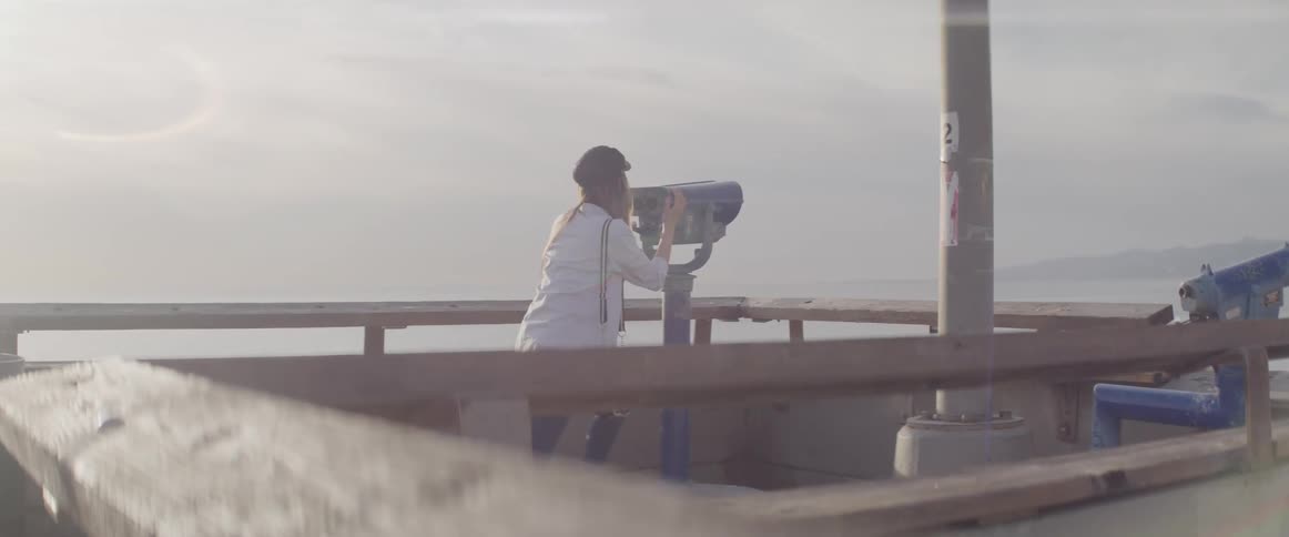A woman bends down to peer through a pair of binoculars