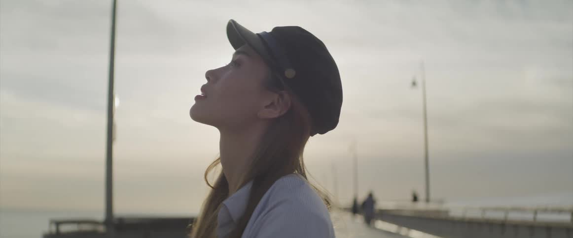 Young woman on pier looking towards the sky