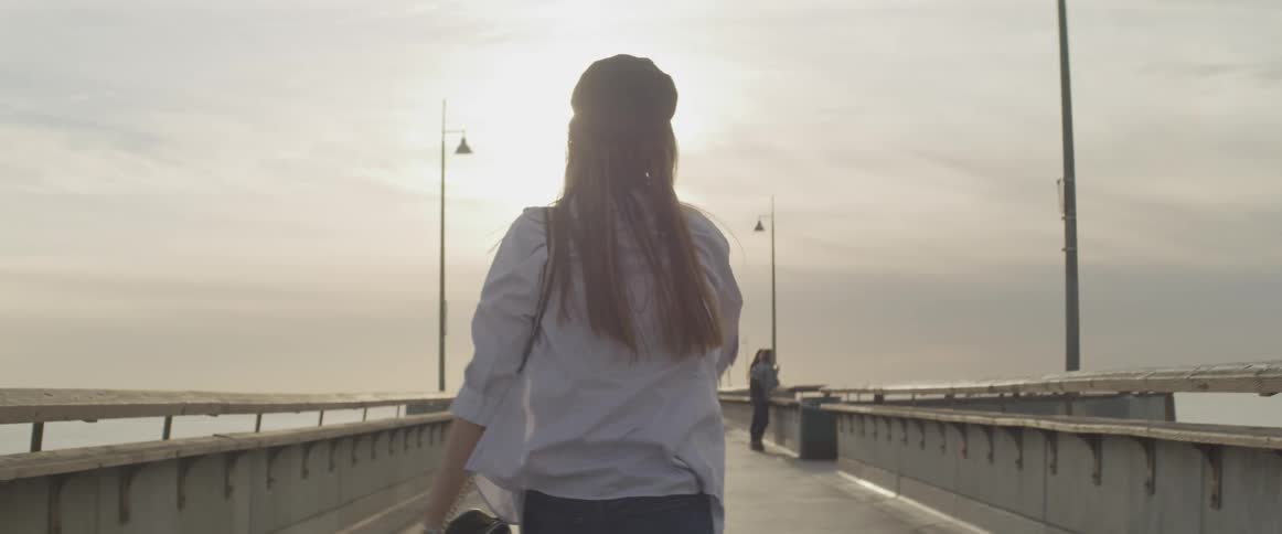 A woman walks happily across a pier and spins around