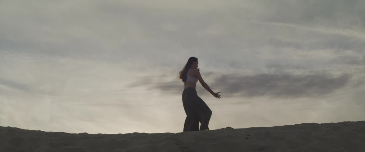 A teenage girl practices martial arts on the beach