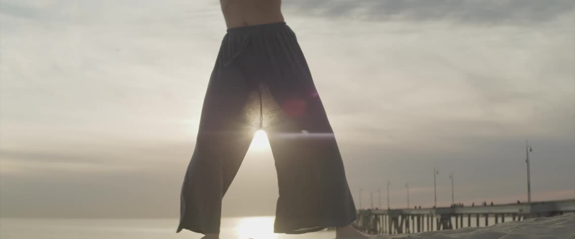 An asian woman on the beach performing karate moves