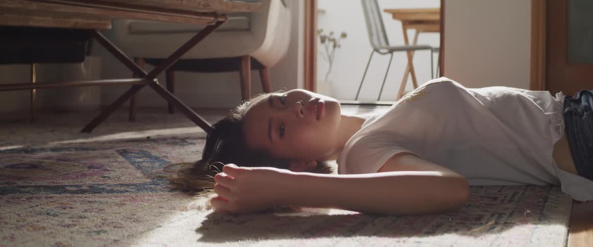 A teenage girl lying on the floor at home plays with her hair