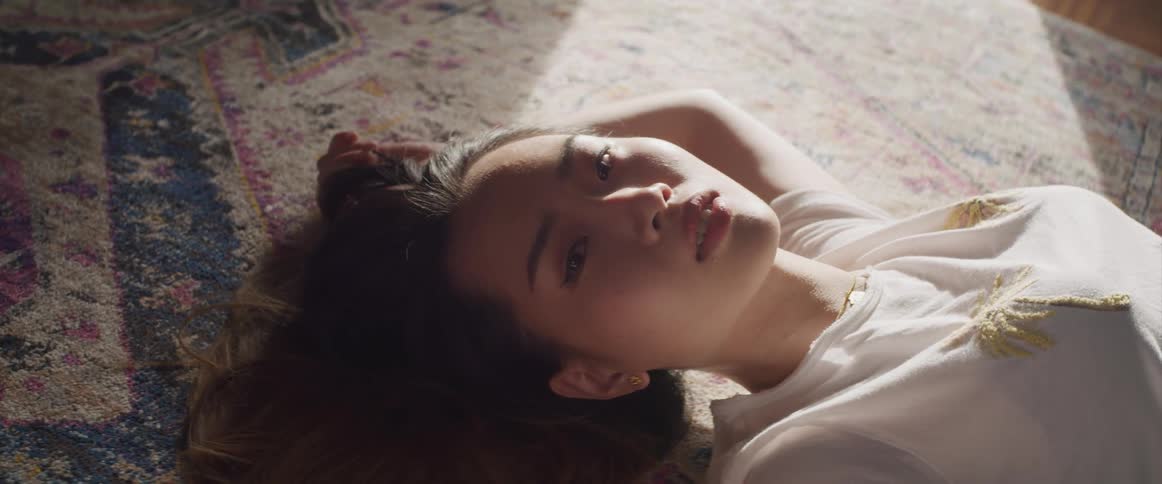 A young asian woman poses as she lays on her back one a large rug