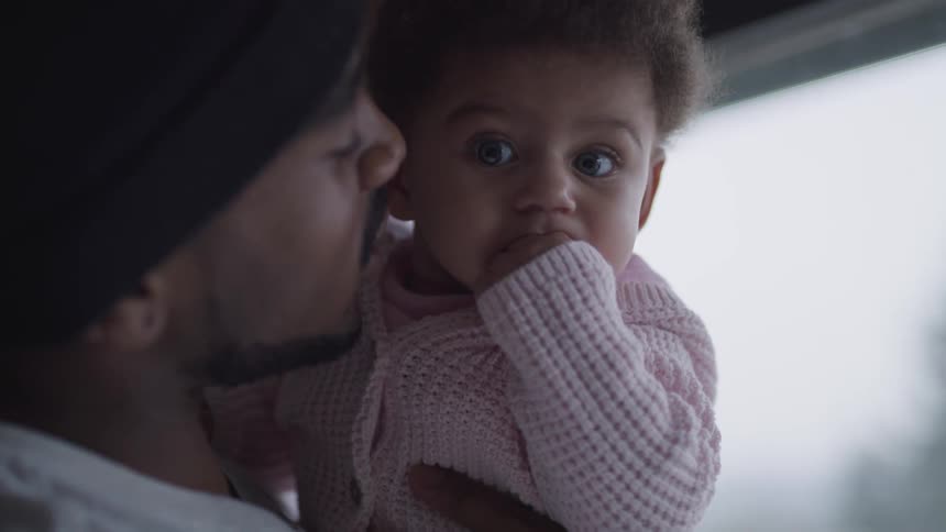 A man gives his daughter a kiss in his arms