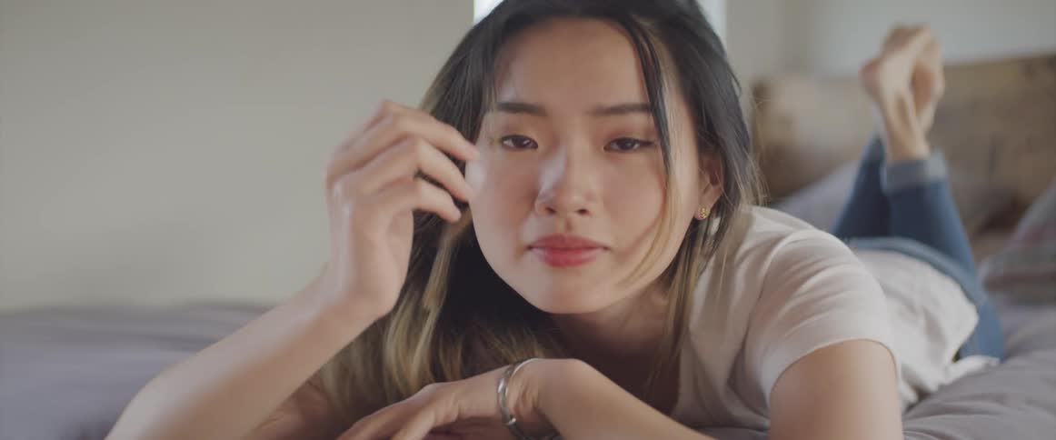An asian female laying on a bed smiling