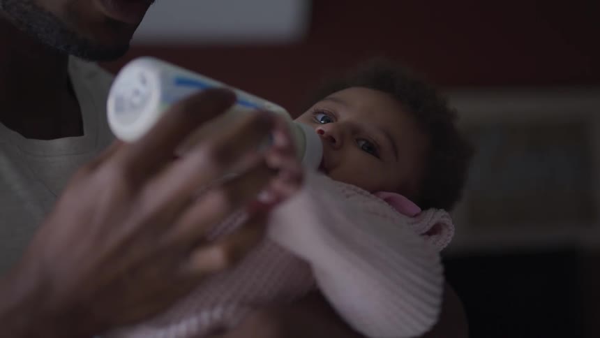 Father feeding baby milk from a bottle