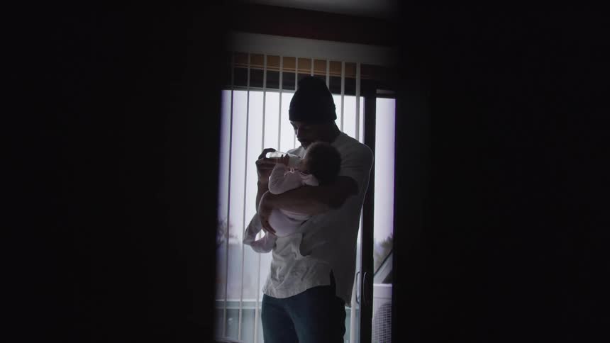 Father feeds a baby while holding it lovingly in his arms at nome
