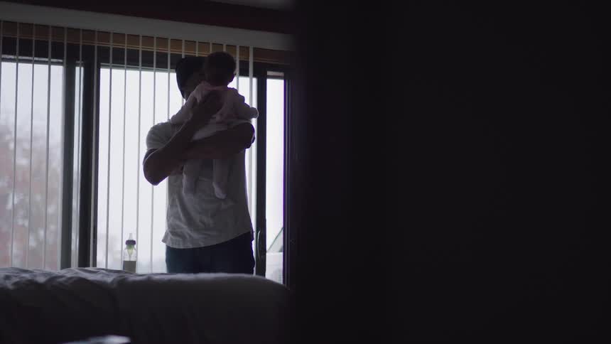 A young man at home rubs his babies back