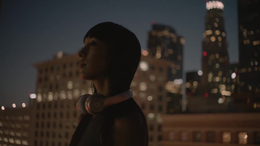 A woman with dark hair takes off her headphones