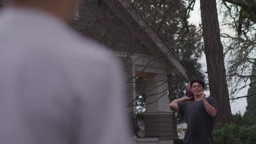 Father and son playing football on the backyard at home