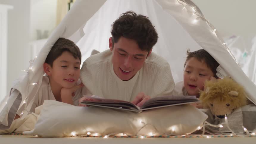 A teenage boy reads a book to his brothers