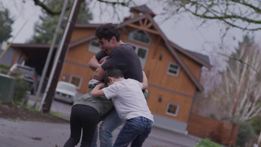 A father playing football with his two sons outside their home