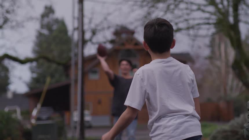 Three brothers play football together in a back yard