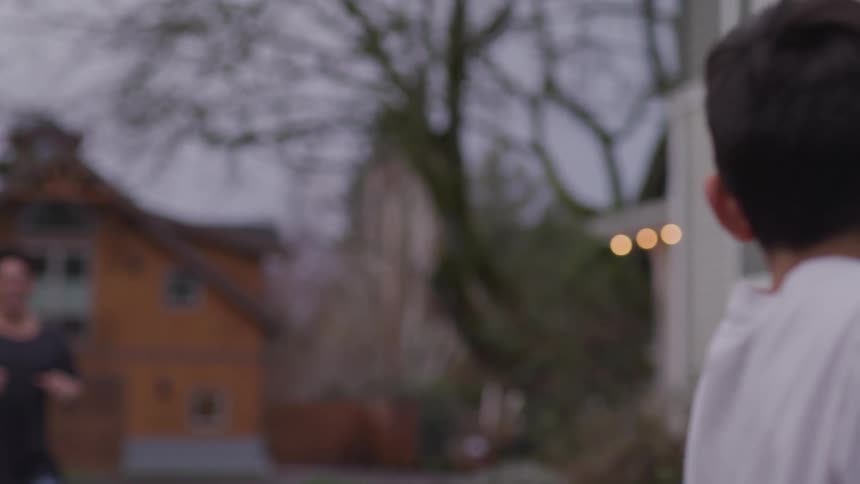 A boy throws a football to a teenage brother in their back yard