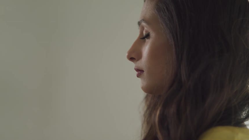 Side view of a woman with brown wavy hair and eyes closed