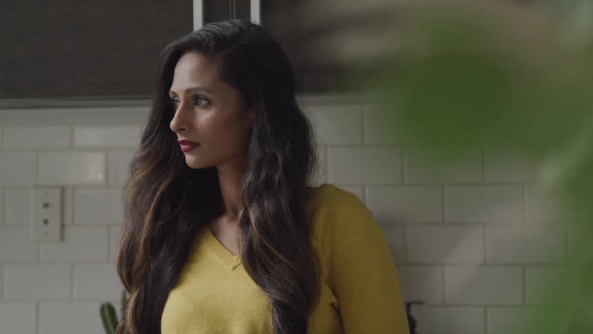A woman in a yellow shirt is standing next to a white cement block wall