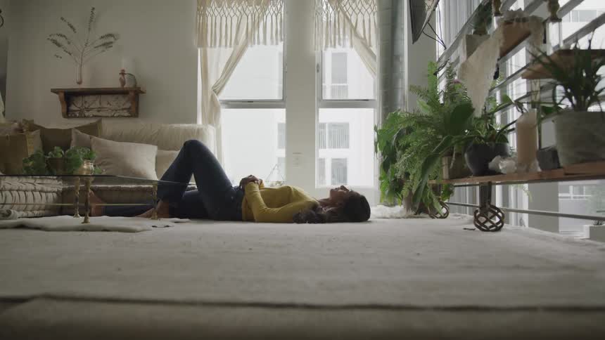 A woman lays on the floor of her living room