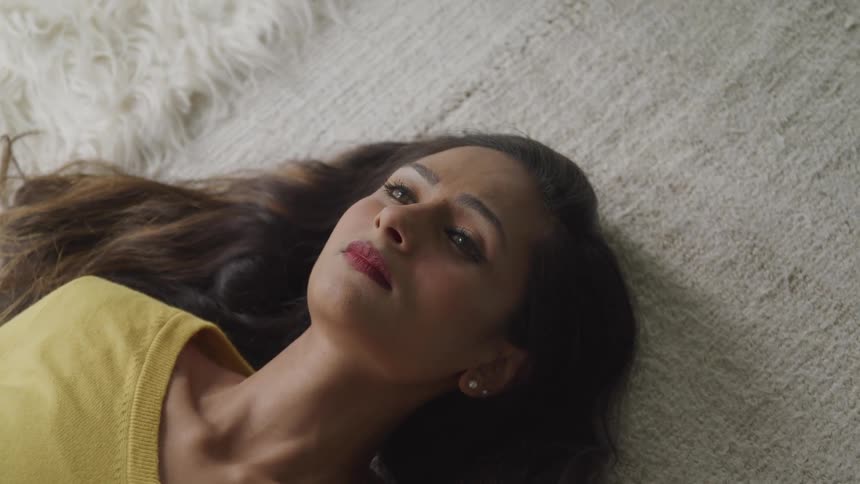 A woman is laying on the ground on a rug