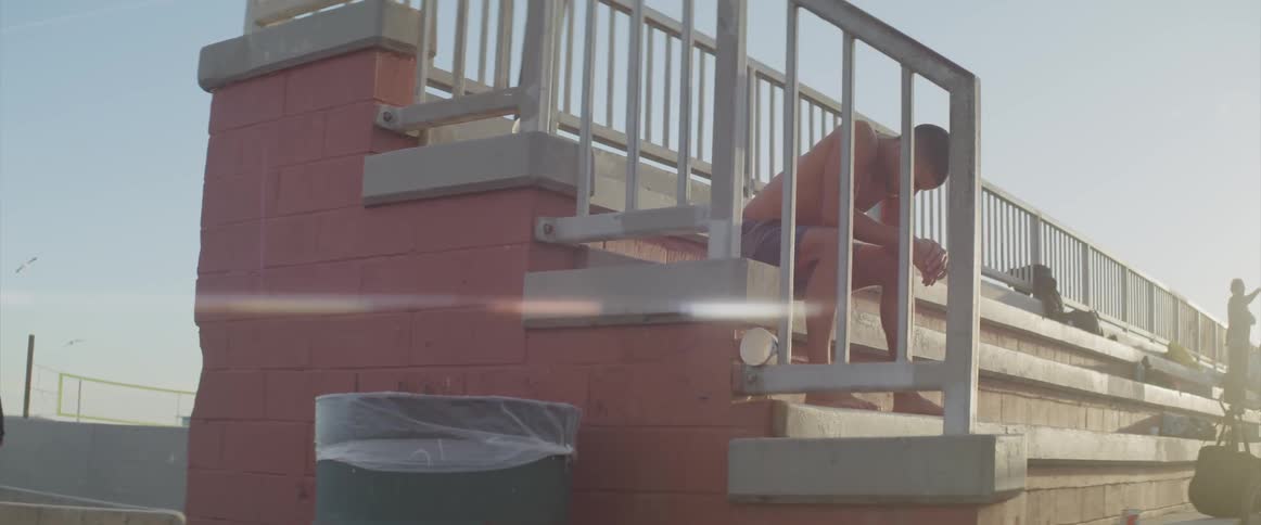 A person sits quietly on outside park bleachers