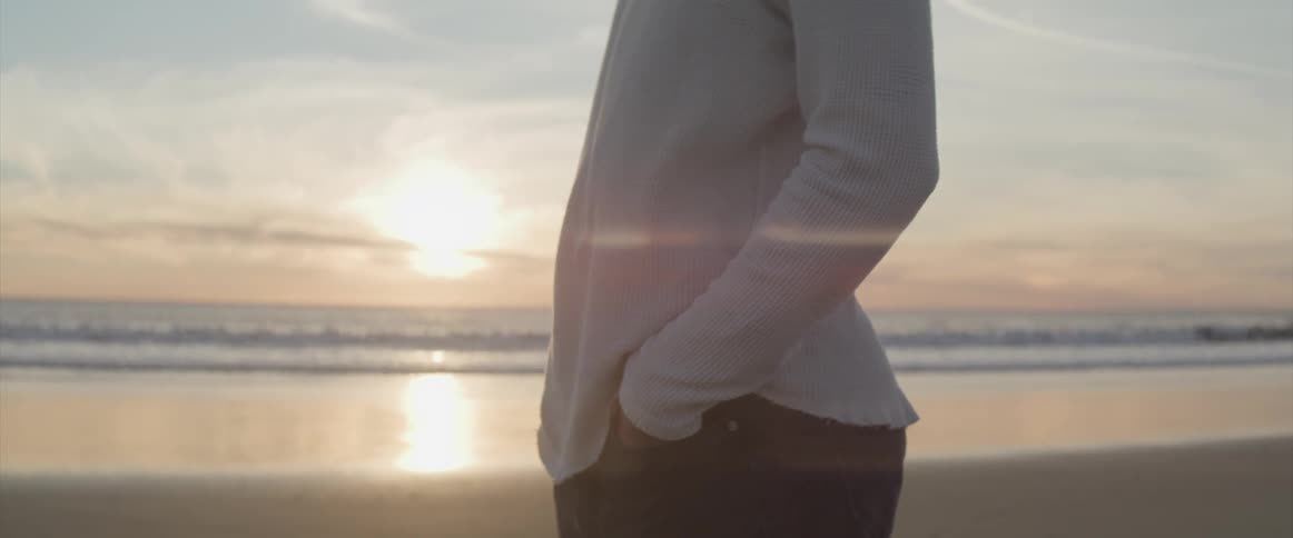 A woman is standing outdoors at the beach