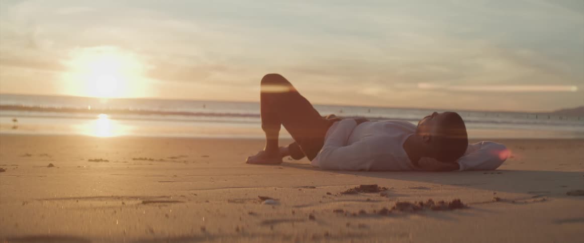 A young man lying on the beach at dusk