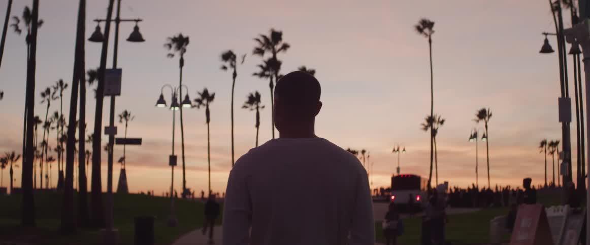 A man standing on a walkway with trees the sky and clouds in the background