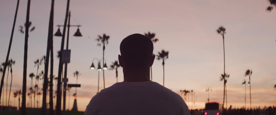 A male walking down the road near palm trees