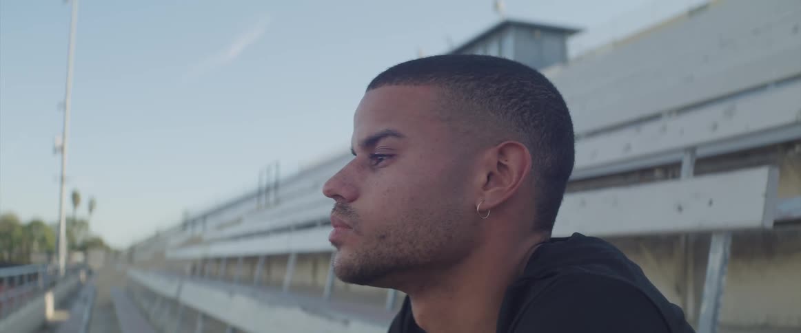 A teenage boy sits outside in a stadium