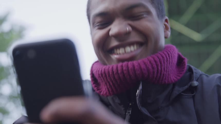 A man smiles and laughs after reading a message on his smart phone