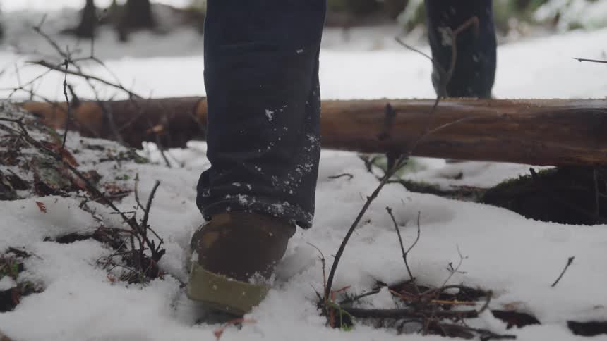 A person with boots walking in the snow and ice
