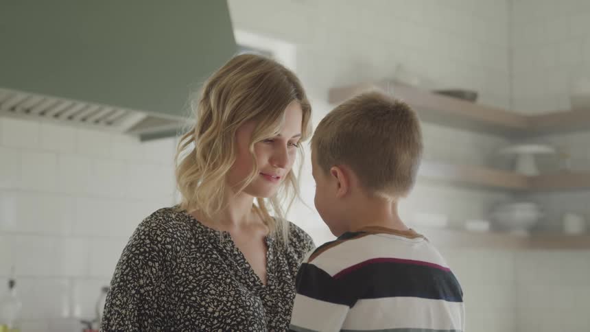 A woman kisses her young son on his forehead