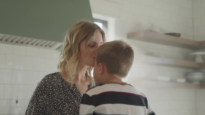 A mother kisses her son on the forehead