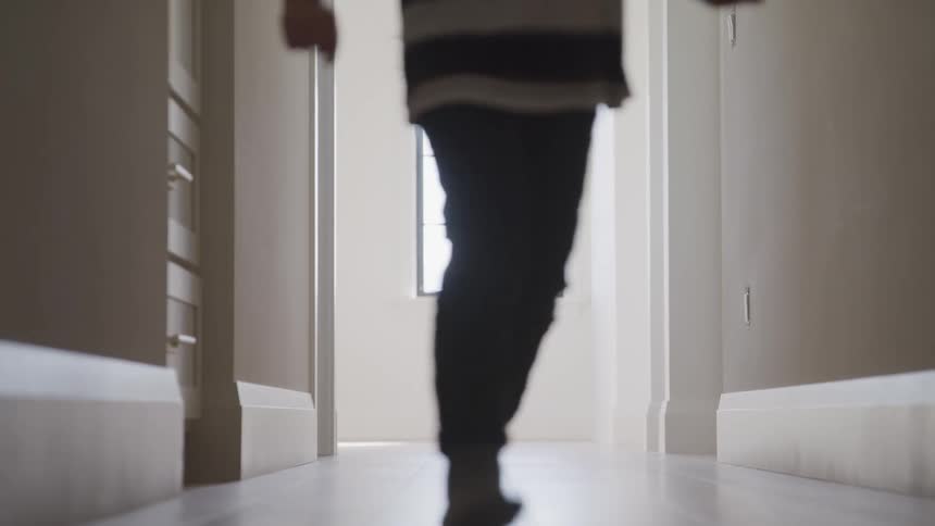 A young boy runs down a hallway at home