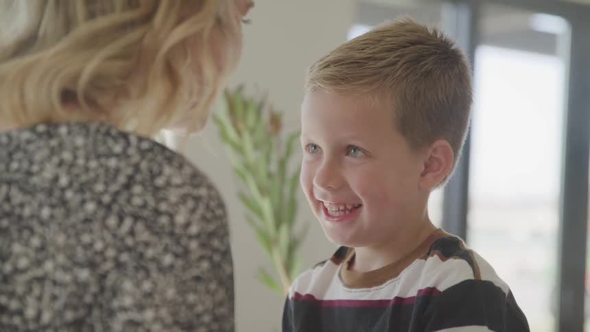 A smiling boy kisses his mother