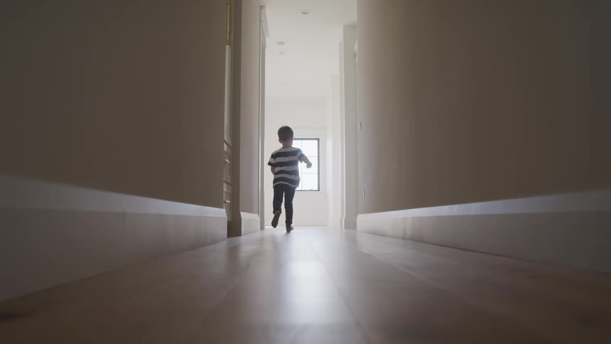 Child runs down house hallway with wooden floor
