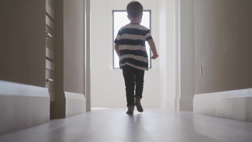 Boy running barefoot on a corridor at home