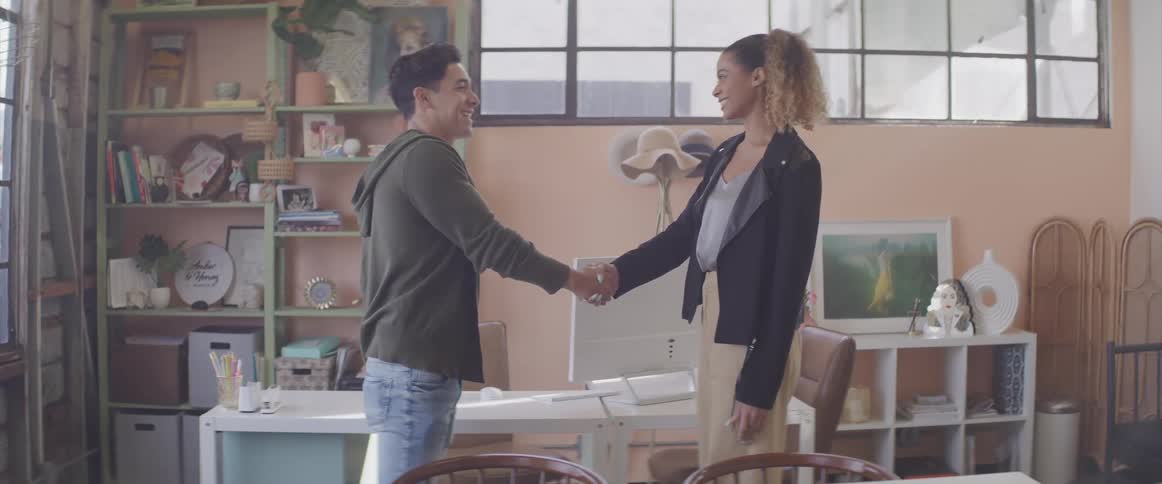 A man and woman are shaking hands in a room