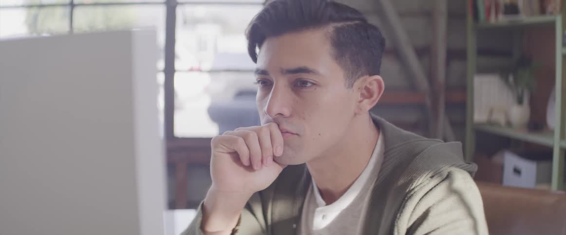 A male sitting at a table reading on a computer