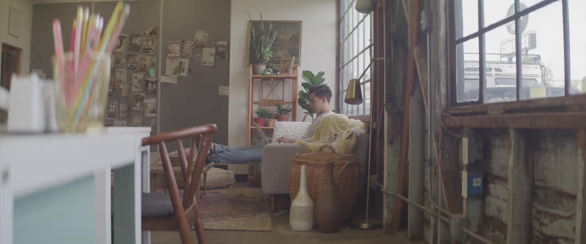 A man sits quietly on a couch in an apartment living room