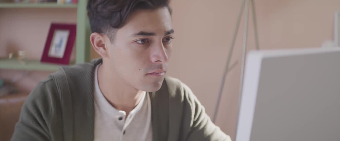 Man studies computer monitor in office near shelves
