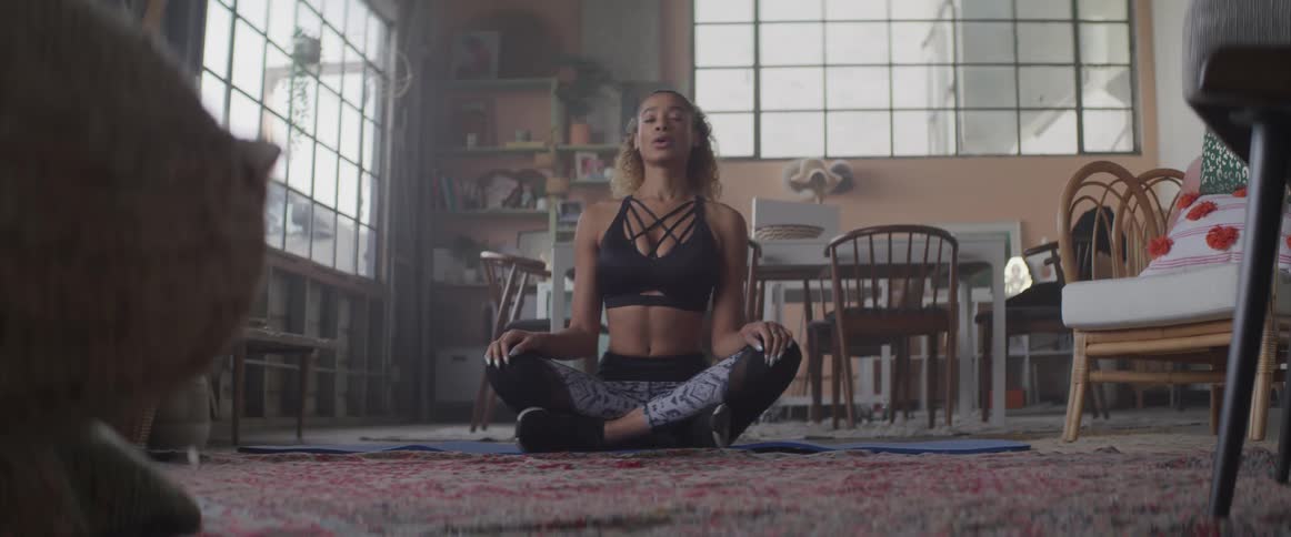 A woman sits in silent meditation in an apartment living area
