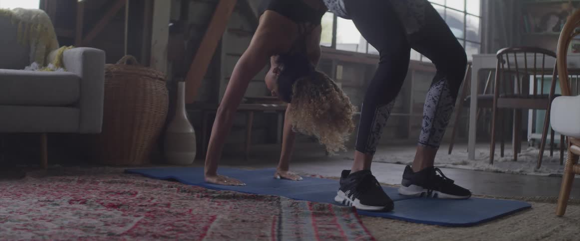 A woman bends backwards in a yoga pose in her home