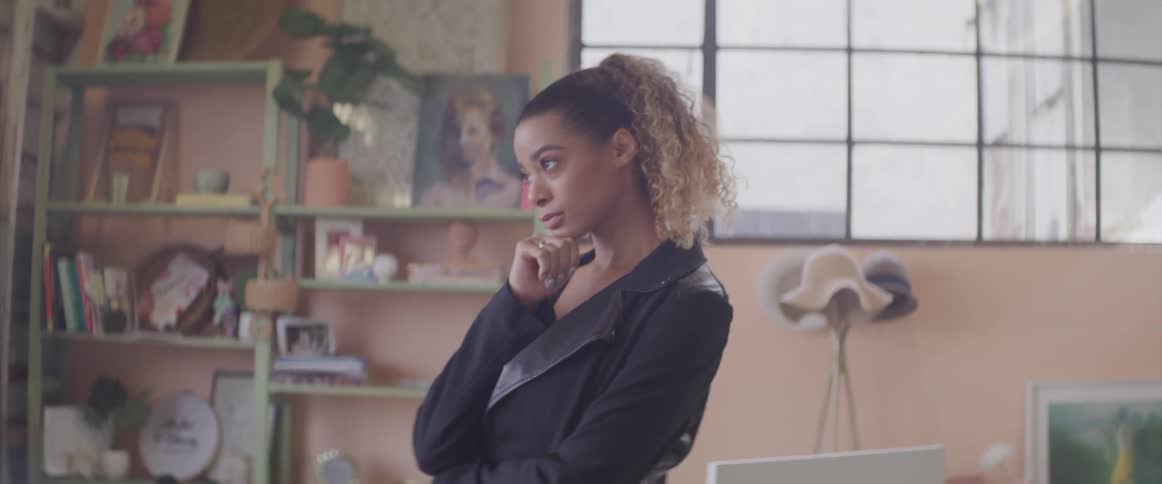 A teenage girl at home walks through a room and looks out the window