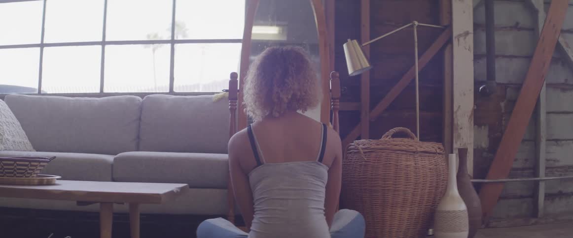 A woman is sitting on the floor by the couch
