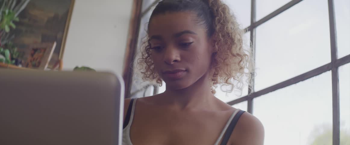 A teenage girl sits inside near a window