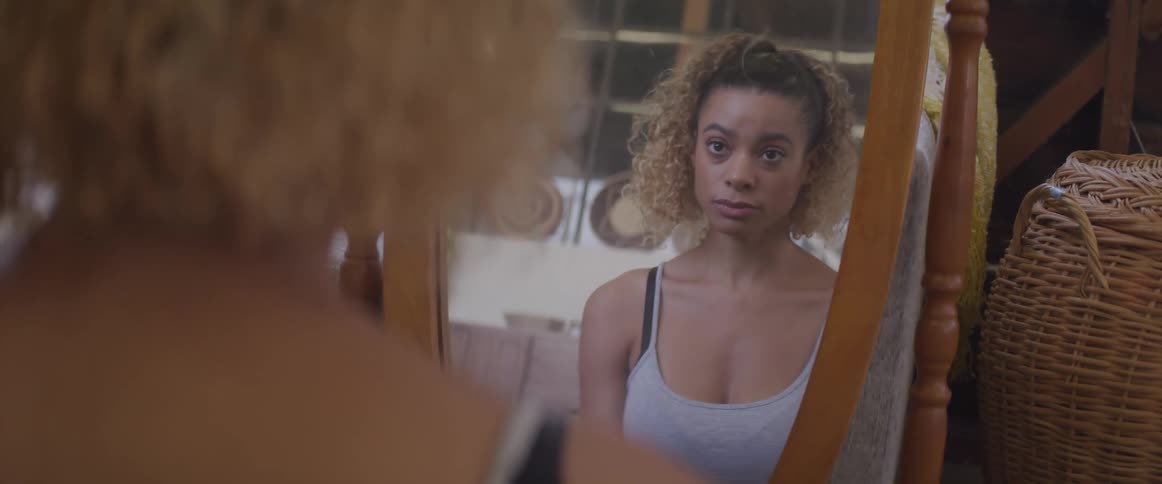 A teenage girl at home looks at herself in a mirror