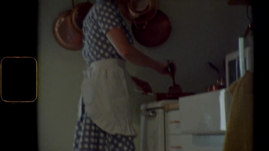 A woman stands at the stove stirring food with a spatula